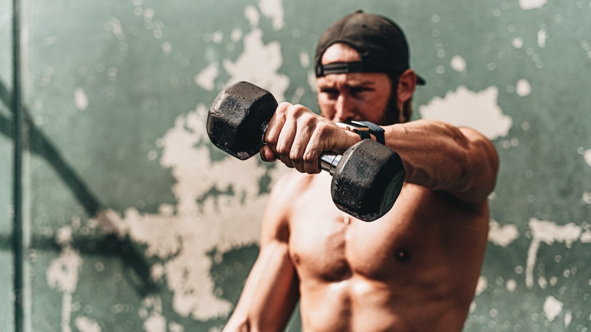 topless man holding black dumbbell